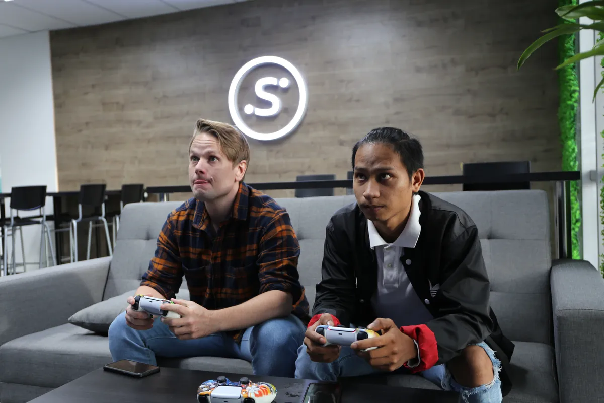 Två kollegor spelar TV-spel i kontorets lounge